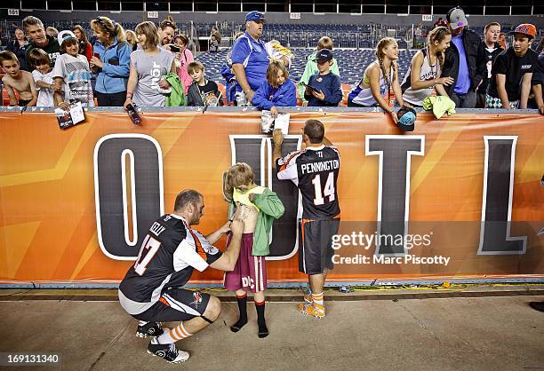 Anthony Kelly of the Denver Outlaws signs autographs for fans with teammate Justin Pennington after a win against the Rochester Rattlers during their...