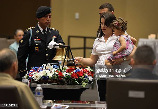 Army Specialist Juan Aguero, from the Florida National Guard Honor Guard, stands beside a bell as Joanna Gonzalez holds her daughter, Ayeleth Garces...