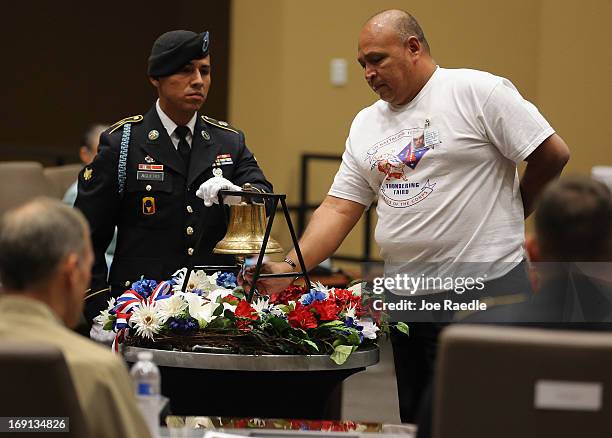 Army Specialist Juan Aguero, from the Florida National Guard Honor Guard, stands beside a bell as William Ortega rings the bell in honor of his son,...