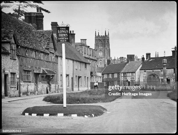 High Street, Steeple Ashton, Wiltshire, 1932. A view looking north past the inn sign for The Longs Arms, showing houses on the High Street with the...