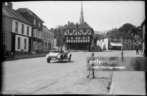 Town Street, Thaxted, Uttlesford, Essex, circa 1920. A view looking north-west along Town Street in Thaxted towards the Guildhall, with a car driving...