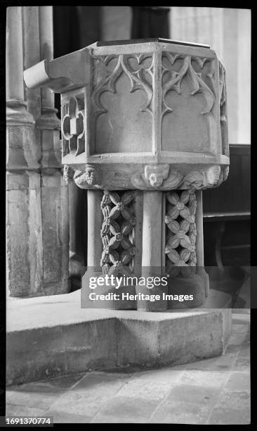 St Andrew's Church, Churchyard, Market Place, Castle Combe, Wiltshire, 1940-1949. Detail of a 14th century octagonal stone font with panelled reliefs...