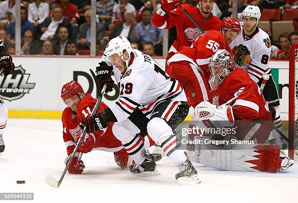 Jonathan Toews of the Chicago Blackhawks tries to get to the puck in front of Jimmy Howard and Daniel Cleary of the Detroit Red Wings during the...