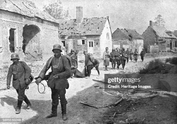 Travers le champ de bataille; prisonniers allemands traversant un village reconquis; a l'exception du blesse que deux camarades soutiennent a...