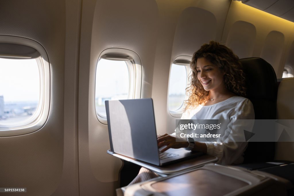Airplane passenger working on her laptop while traveling