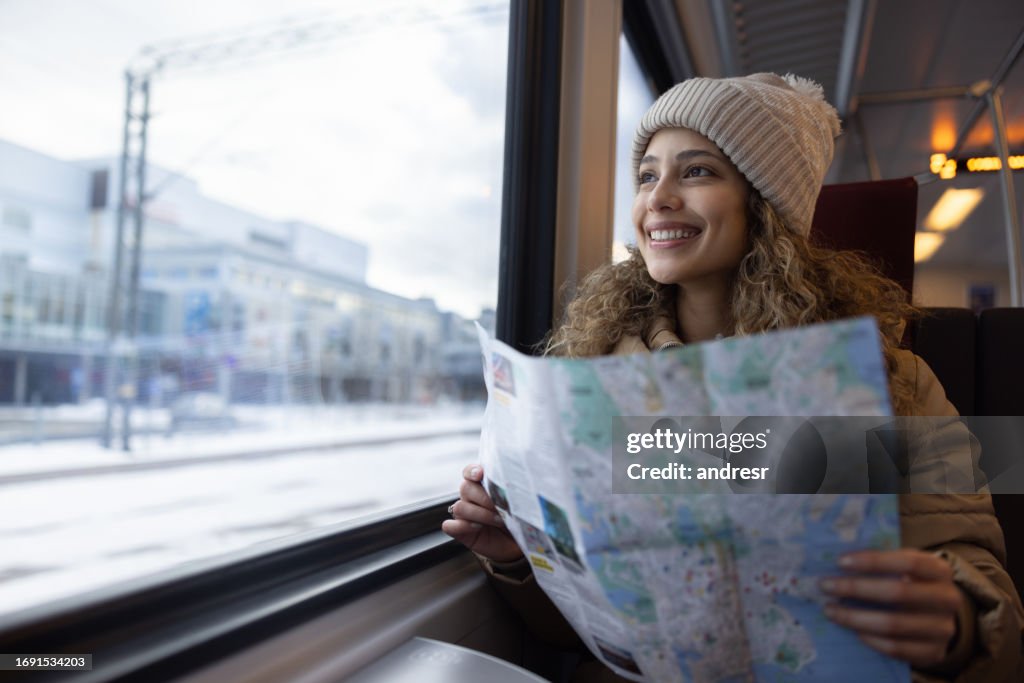 Happy tourist traveling by train and holding a map