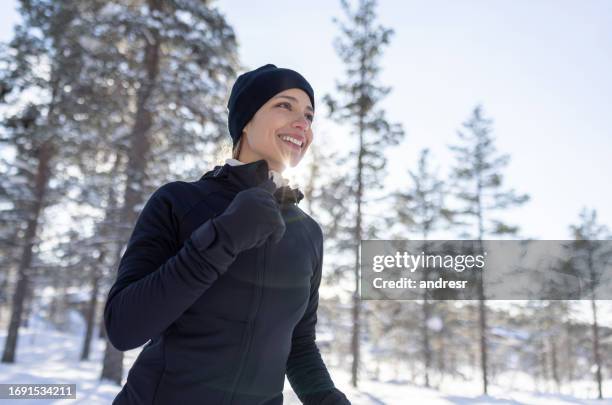 frau, die im winter im freien läuft und glücklich aussieht - winter sport stock-fotos und bilder