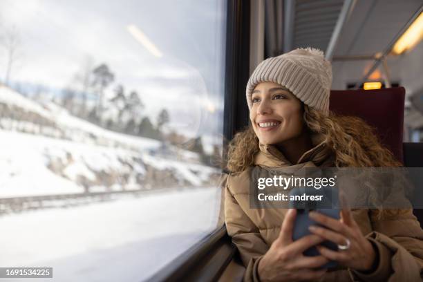 woman riding the train in the winter while using her phone - commuter train stock pictures, royalty-free photos & images