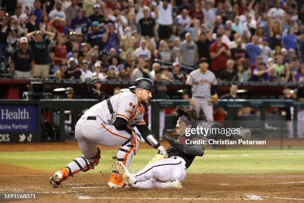 Corbin Carroll of the Arizona Diamondbacks slides into home plate to score on an error past catcher Patrick Bailey of the San Francisco Giants during...