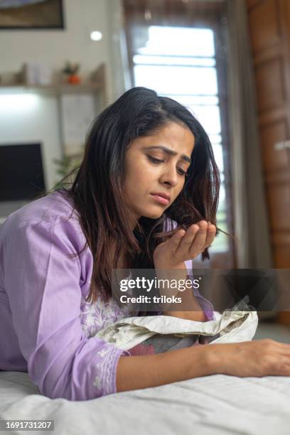 woman looking at her fallen hair while lying on bed - falling stock pictures, royalty-free photos & images