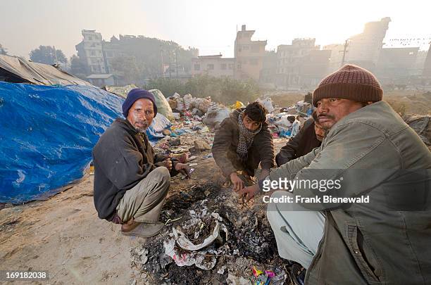 Low caste people sitting around a fire on the garbage dump at Bhagmati River in the middle of the city. The garbage collected off the streets of the...