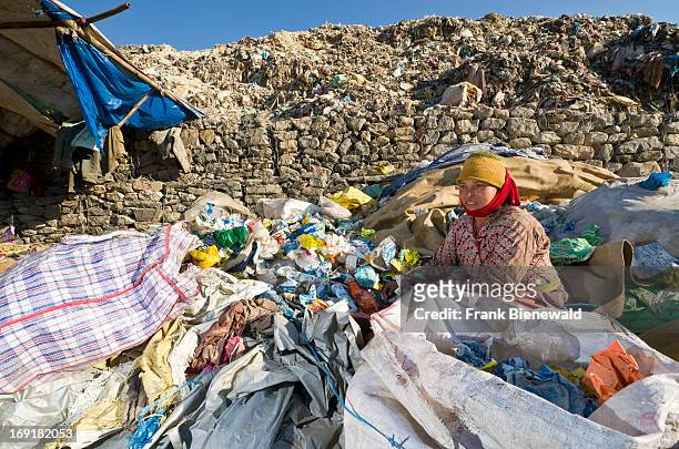 Woman sitting in between and sorting out garbage at the Aletar garbage dump. The garbage collected off the streets of the capital city is mostly...