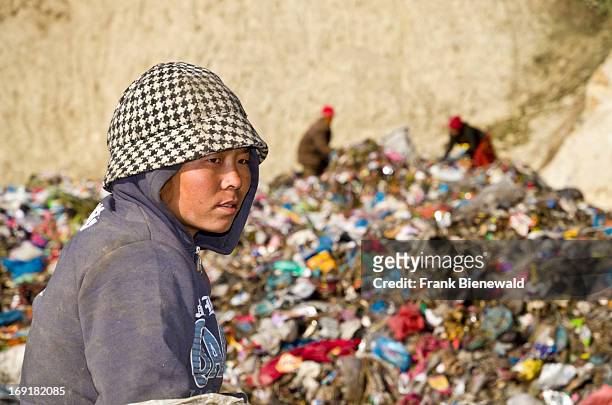 Portrait of a woman sorting out garbage at the Aletar garbage dump with two more workers in the back. The garbage collected off the streets of the...
