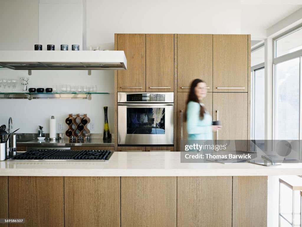 Woman walking through kitchen of modern home