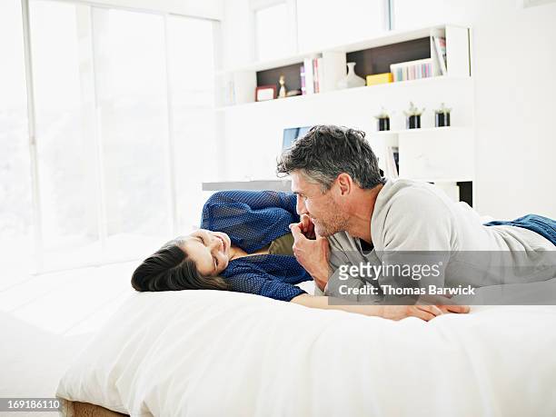 smiling couple talking on bed in modern home - materasso foto e immagini stock