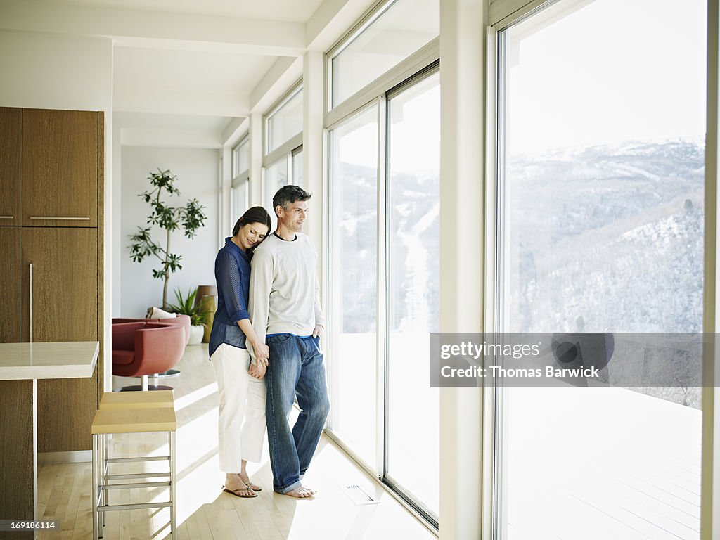 Couple embracing near windows in contemporary home