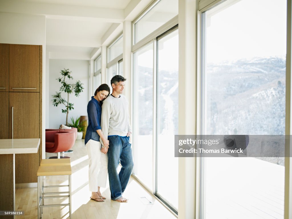 Couple embracing near windows in contemporary home