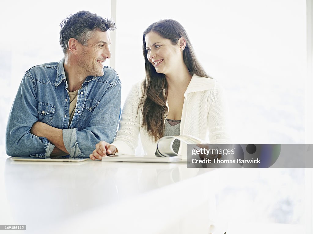Smiling couple reading at counter in home