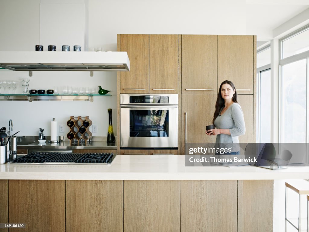 Woman holding tea in kitchen of contemporary home