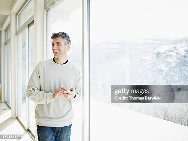 smiling man leaning against window in home - utah house stock pictures, royalty-free photos & images