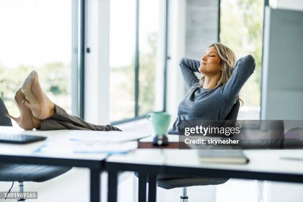 relaxed businesswoman having a break in the office. - hands behind head stock pictures, royalty-free photos & images
