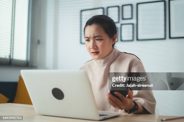 mujer asiática que usa computadora portátil y teléfono inteligente que sufre de problemas con el trabajo o las finanzas. - quejándose fotografías e imágenes de stock
