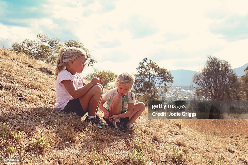 Children sitting on a grassy hill in afternoon sun