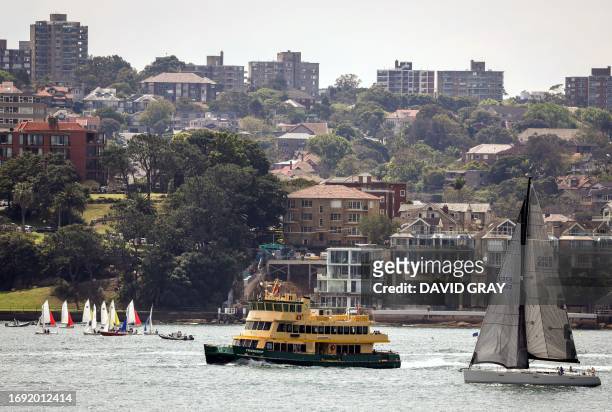 Apartment blocks and houses can be seen behind sailing boats and a ferry on Sydney Harbour on September 27, 2023.