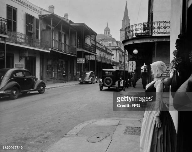 Mannequin dressed in a period outfit with a slat lace bonnet on display outside a store, with cars parked along Chartres Street in the French Quarter...