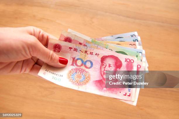 woman holding chinese yuan banknotes - money-talks-englische-redewendung stock-fotos und bilder
