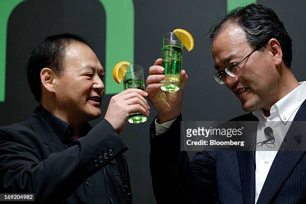 Peter Chou, chief executive officer of HTC Corp., left, makes a toast with Takashi Tanaka, president of KDDI Corp., at the unveiling event for the...