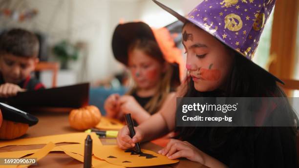 small children friends making halloween decorations during house halloween party gathering - halloween craft stock pictures, royalty-free photos & images