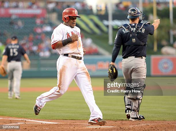 Erick Aybar of the Los Angeles Angels scores a run off of a Albert Pujols single in front of Kelly Shoppach of the Seattle Mariners for a 1-0 lead...