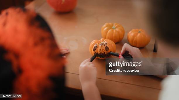 small girl making halloween decorations with her mother in living room at home - halloween craft stock pictures, royalty-free photos & images