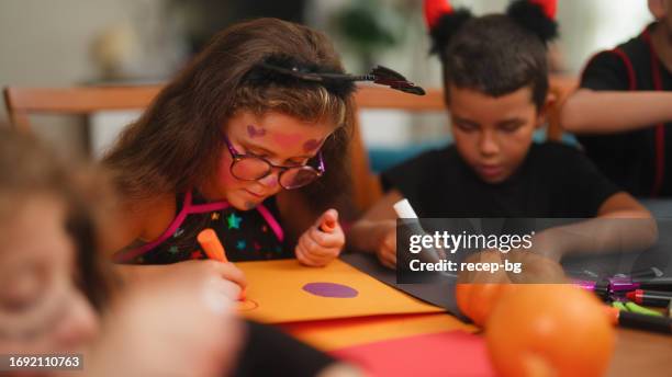 kleine kinderfreunde, die halloween-dekorationen während des halloween-party-treffens im haus herstellen - kunst und handwerkserzeugnis stock-fotos und bilder