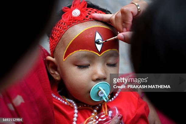 Woman applies make-up to a girl dressed as a living goddess 'Kumari' as she prepares to take part in the 'Kumari Puja' rituals at the Hanuman Dhoka...