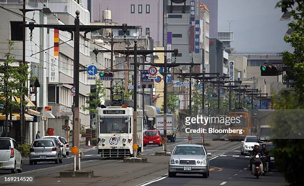 Trams travel along a road in Okayama, Japan, on Tuesday, May 21, 2013. The Bank of Japan, forecast to maintain plans for expanded monetary easing at...