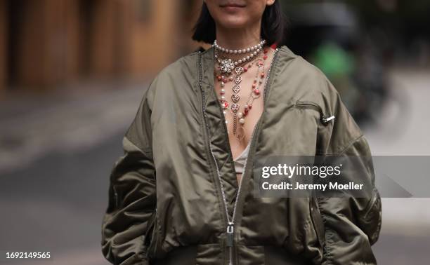 Fashion Week Guest was seen wearing a grey denim Miu Miu skirt, a black fendi bag with golden writings, a green bra, a green oversized jacket, a blue...