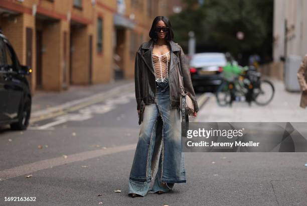 Fashion Week Guest was seen wearing dark Loewe shades, a brown bra under a silver net as a top, an oversized brown jacket, a beige loewe puzzle bag...