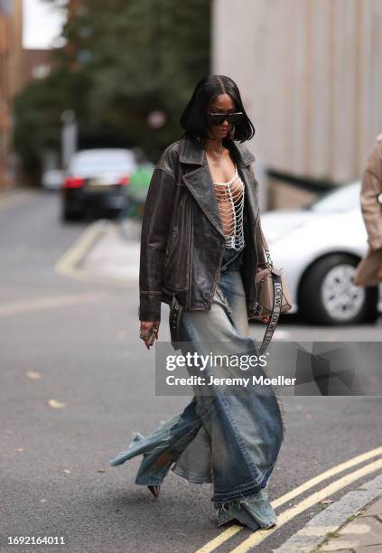 Fashion Week Guest was seen wearing dark Loewe shades, a brown bra under a silver net as a top, an oversized brown jacket, a beige loewe puzzle bag...