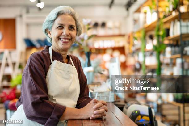 build diversifying customer bases and sustaining your quality of service as a small business owner. portrait of a proud senior female flower shop owner leaning in front of a counter checkout. - personalized stock pictures, royalty-free photos & images