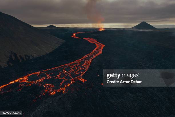 aerial view of the dramatic eruption in iceland of the new litli-hrutur volcano with meander river of lava. 2023. - aardkorst stockfoto's en -beelden