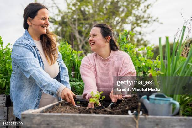mother and daughter with down syndrome having fun while working on garden - syndroom van down stockfoto's en -beelden