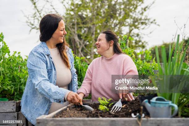 young adult woman with down syndrome working on garden - down syndrome stock pictures, royalty-free photos & images