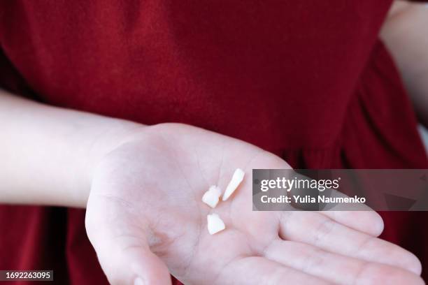 close-up of a baby's teeth held in the hand of a little girl. - losing virginity stock-fotos und bilder