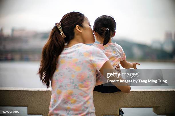 Young mom hugging & whispering to toddler girl