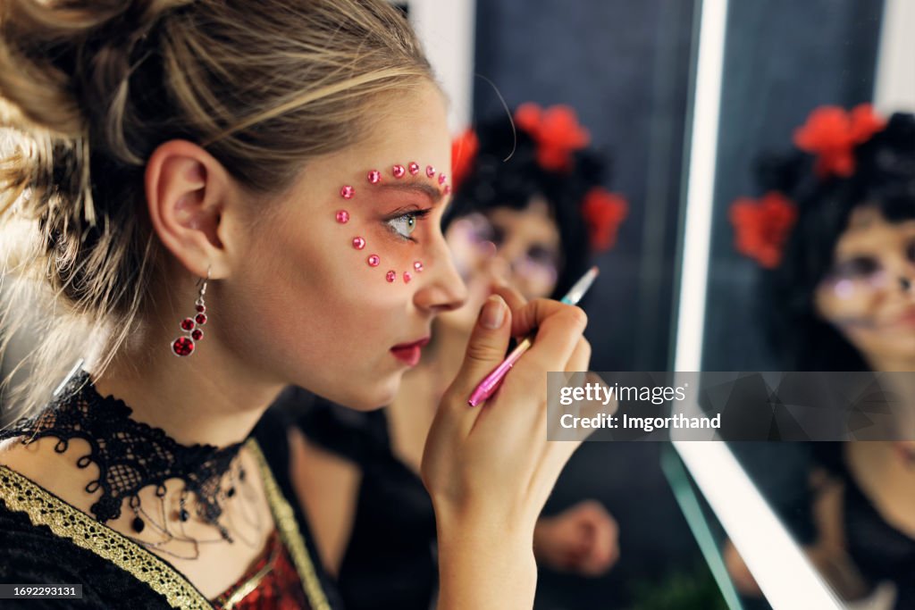 Teenage girl is painting her face for Halloween