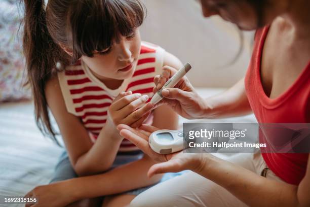 diabetic girl taking finger stick test at home to check blood sugar level. - child diabetes stock pictures, royalty-free photos & images