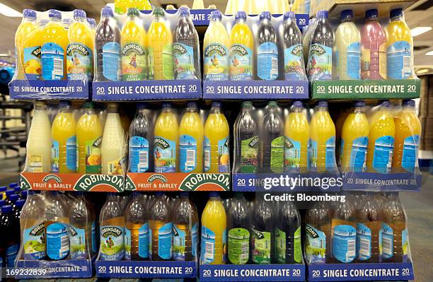 Packaged bottles of Robinsons squash drink, produced by Britvic Plc, sit wrapped in plastic alongside the production line at the company's factory in...