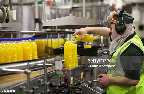 An employee tops up the content in a bottle of Robinsons orange fruit and barley squash drink, produced by Britvic Plc, as it moves along the...